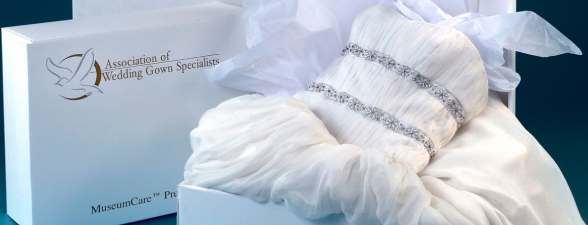 A white wedding gown with jeweled bands is folded in a box labeled 